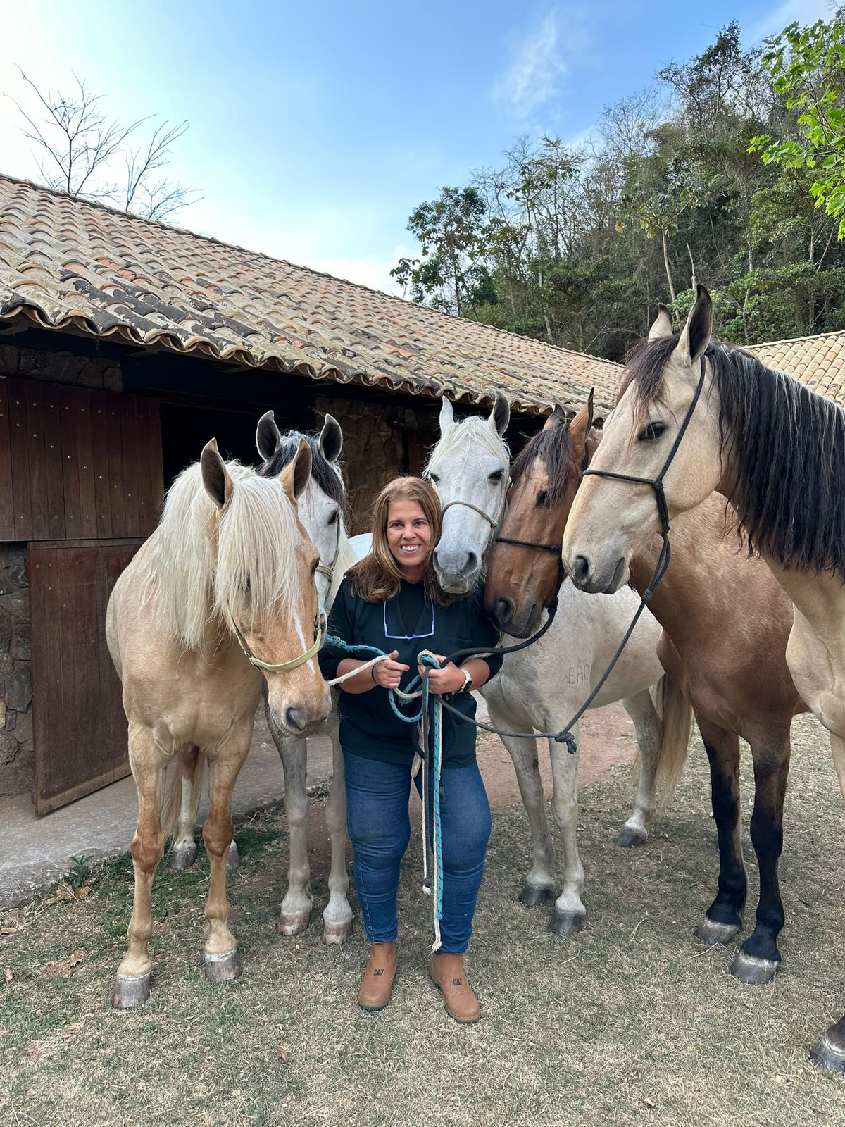 Dra. Christiana com cinco cavalos em frente à cocheira