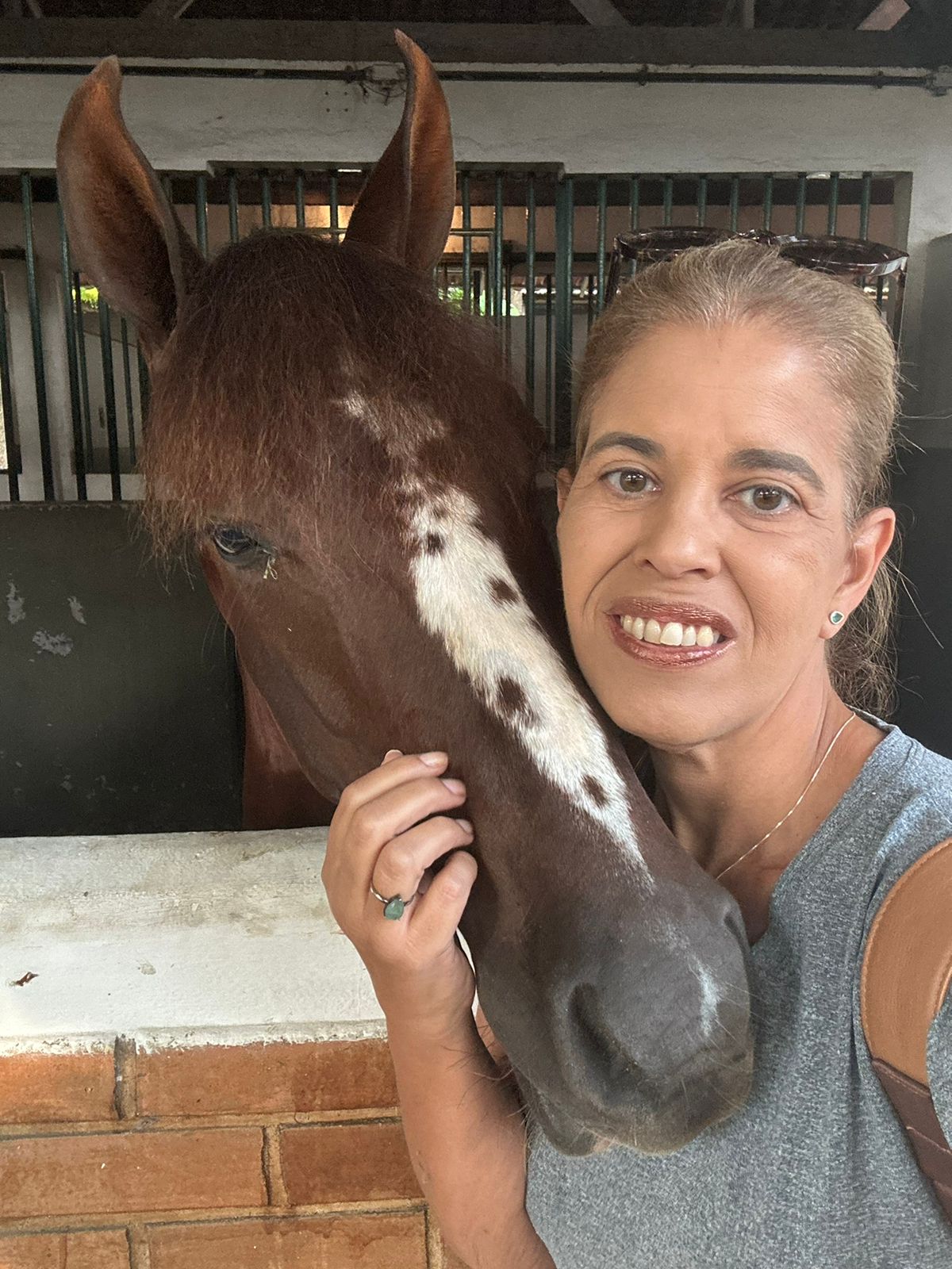 Dra. Christiana ao lado de cavalo na cocheira
